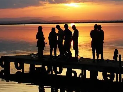 Junge Menschen bei Dämmerung auf einem Ausflug. Junge Menschen am Wasser bei einem Ausflug.
