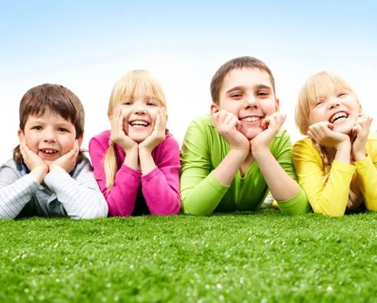 Niños sonriendo tumbados en el césped