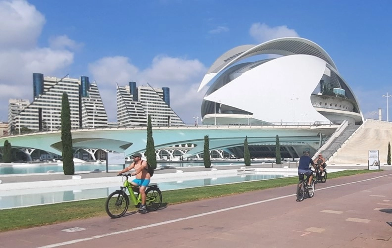 Touristen radeln durch die Stadt der Künste und Wissenschaften in Valencia.