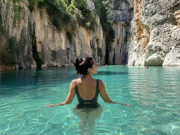 Tourist genießt die natürlichen Badebecken von Montanejos mit türkisfarbenem Wasser, Felsen und mediterraner Natur nahe der Fuente de los Baños.